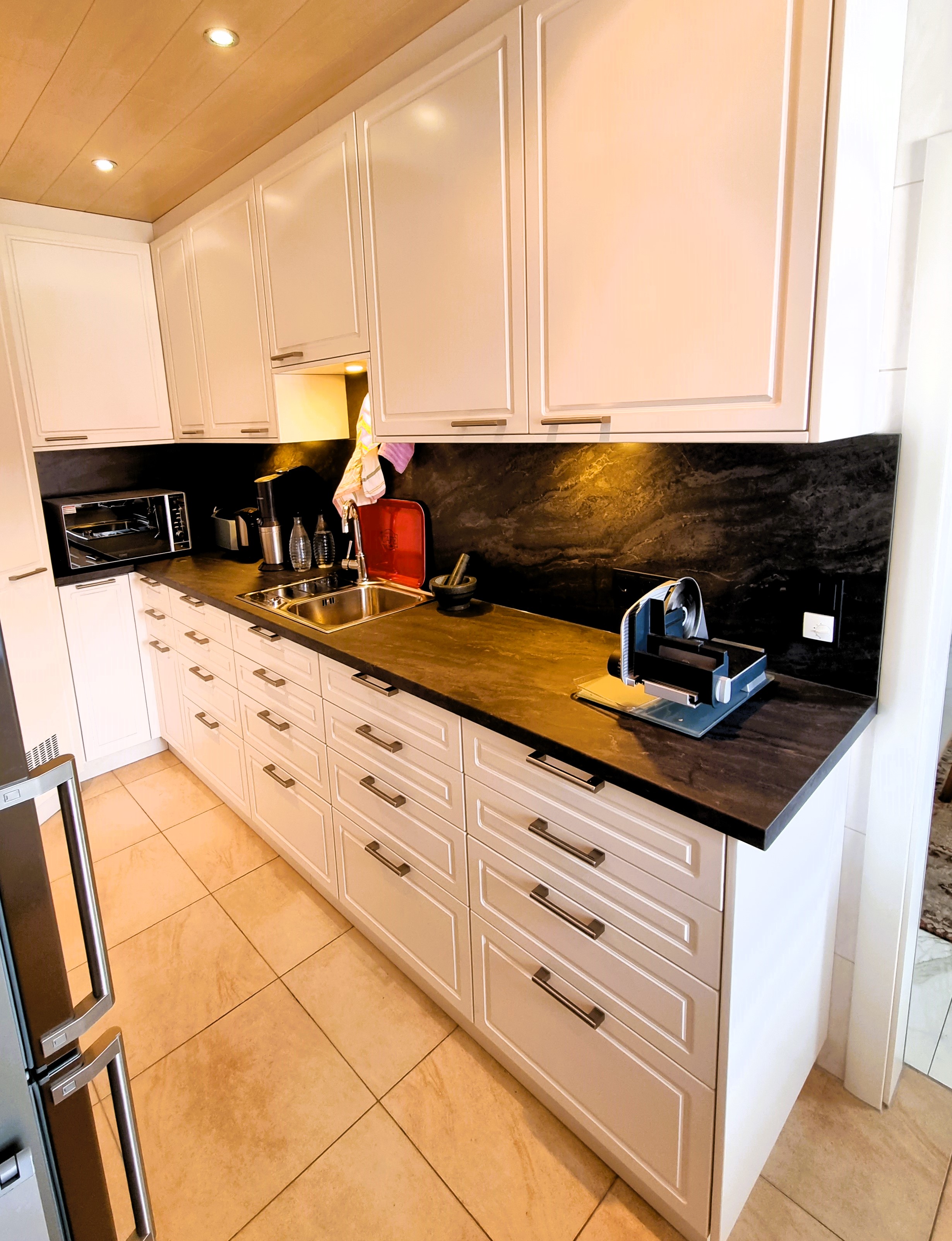 klassische Küche in weiß mit Griffen und dunkler Arbeitsplatte